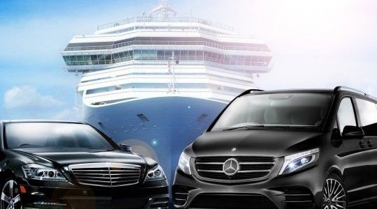 Two luxury vehicles parked in front of a large cruise ship under a bright sky.