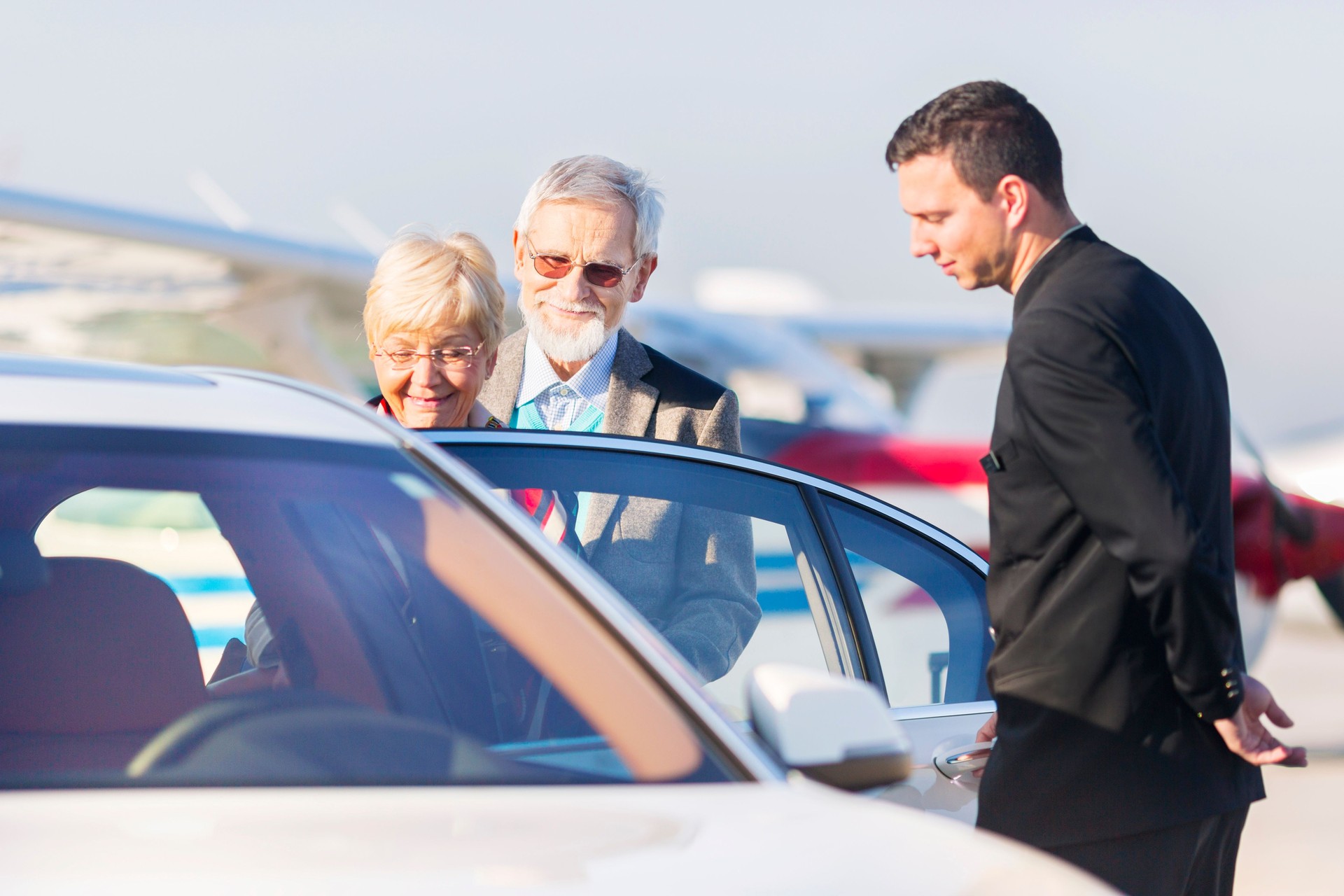 Senior couple leaving airport in chauffeured car